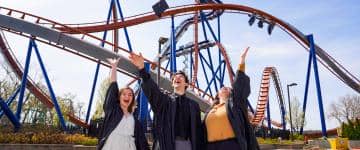 Three college graduates throw their caps in the air celebrating their degrees from Bowling Green State University's Resort and Attractions Management program